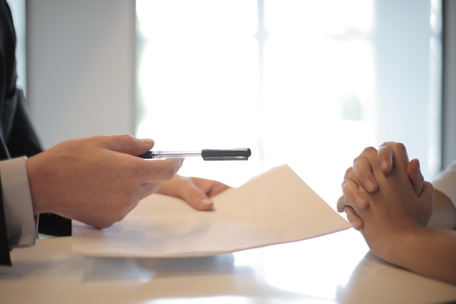 a-person-handing-documents-and-a-pen-to-another-person