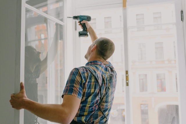 someone fixing a window with a drill